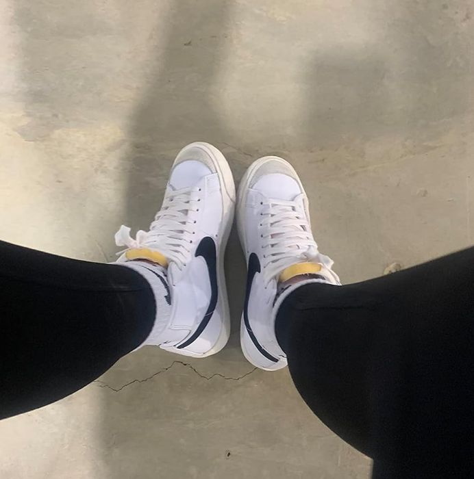 A reviewer showcasing the white and black sneakers