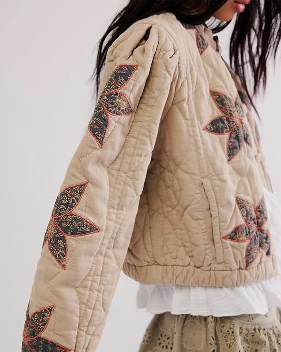 A person wearing a quilted jacket adorned with star-patterned patches on the sleeves and shoulders, paired with a lacy skirt.