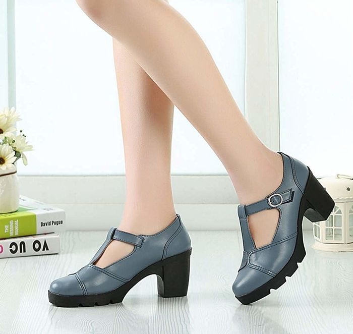 A person wearing gray-blue chunky-heeled shoes with buckle straps