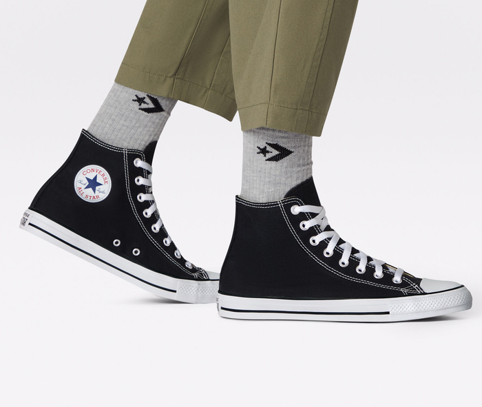 A model showcasing the black and white high-top Converse sneakers.