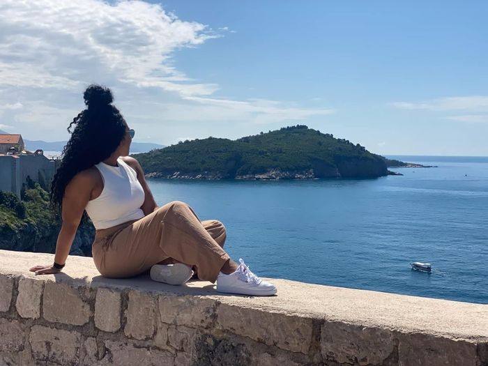 A reviewer sitting on a wall wearing Reebok sneakers