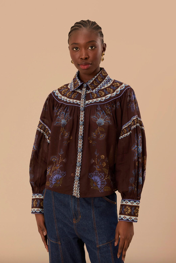 A person wearing a chic patterned blouse with puffed sleeves.