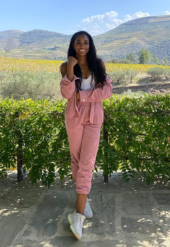 A reviewer wearing salmon-colored corduroy joggers and a matching button-up top.