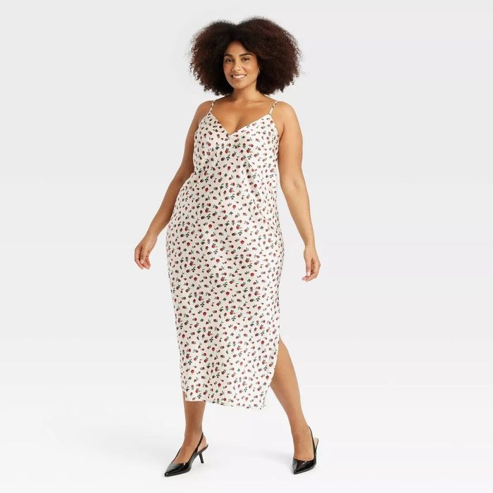 A model wearing a sleeveless, floral-print maxi dress and black heels strikes a pose