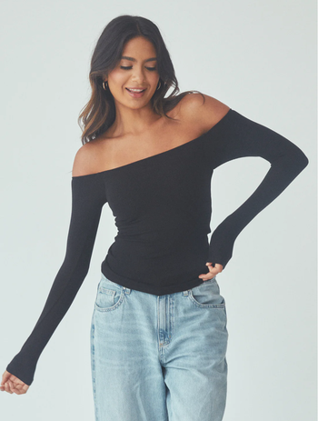 A model wearing a black off-shoulder long-sleeve top styled with light blue jeans.