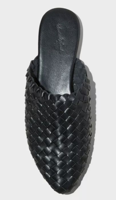 A black woven slip-on shoe displayed on a white background
