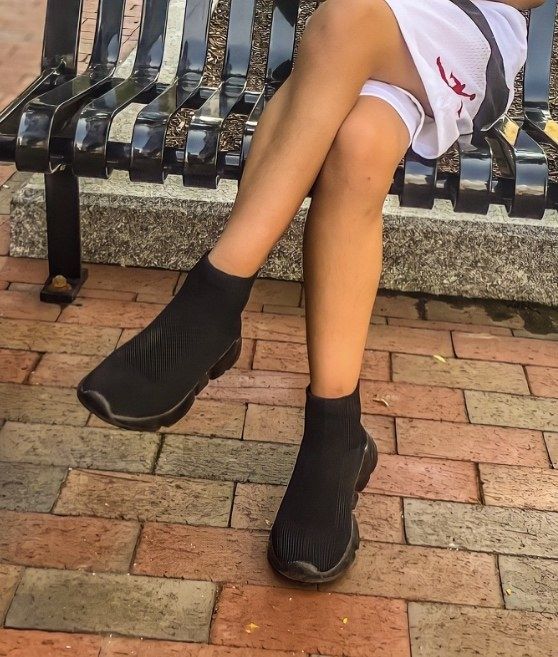 A reviewer wearing black sock-style shoes with black soles