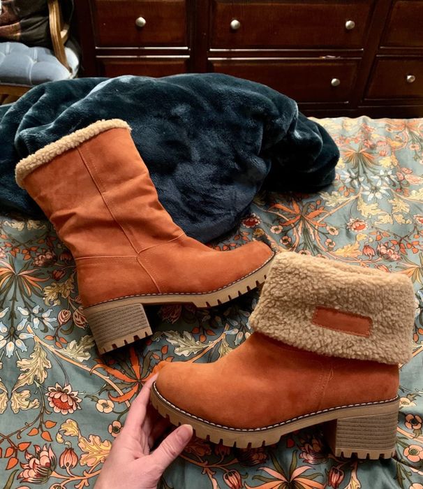 A reviewer showing off the orange boots, one leg folded down and the other left unrolled