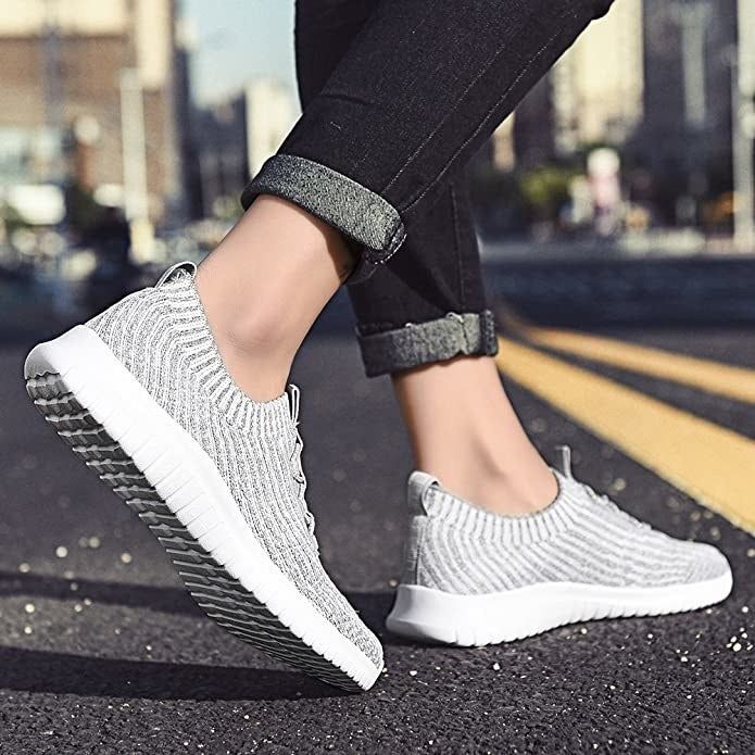A model showcasing lace-free white and gray sneakers while crossing the street