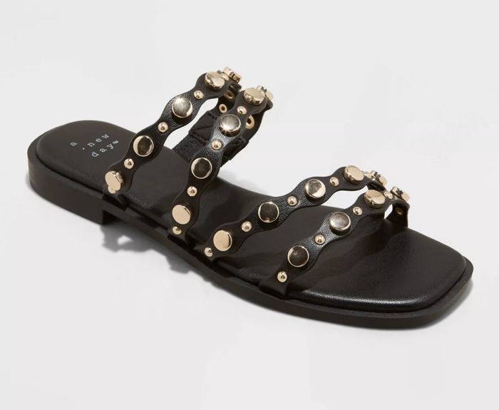 Black sandal featuring metallic embellishments on the straps