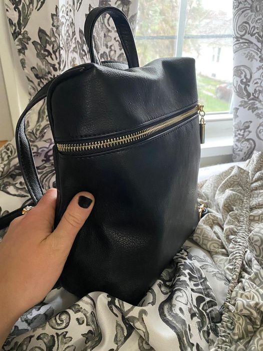Close-up of a reviewer’s leather crossbody backpack with a zipper