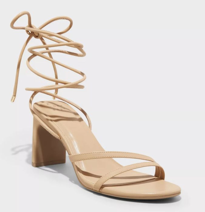 A strappy nude heel with lace-up ankle ties, showcased against a simple background with no person in the image