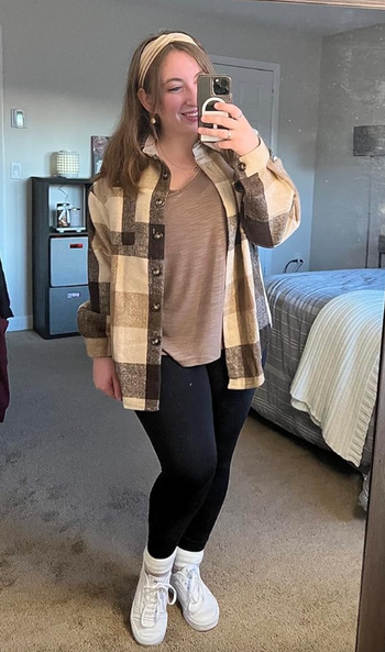 A reviewer wearing a beige and brown plaid button-up shacket.