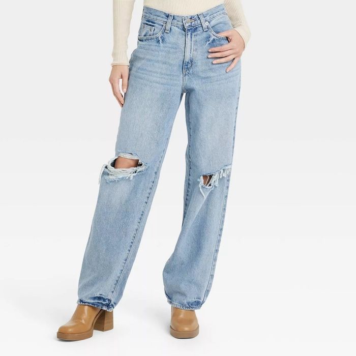 A person wearing high-waisted, relaxed-fit ripped jeans styled with brown platform boots