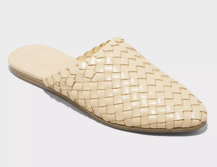 A woven slide shoe placed on a neutral, plain background