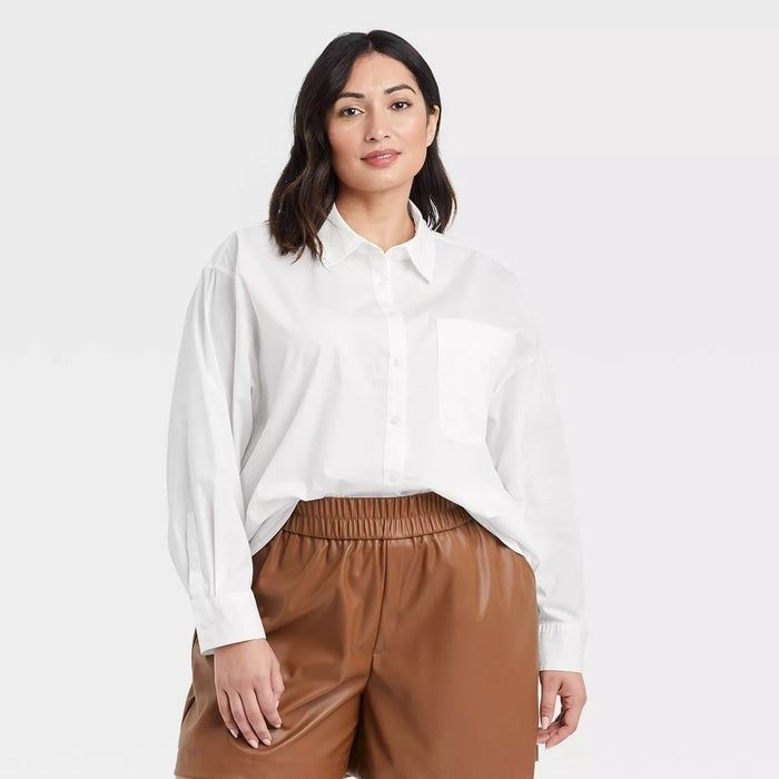 A model dressed in a white button-up shirt paired with brown leather shorts