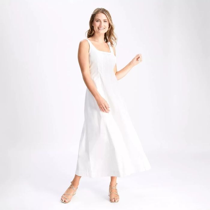 A model wearing a sleeveless, floor-length dress with a square neckline and strappy sandals