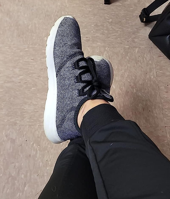 A reviewer showcasing the black and white sneakers