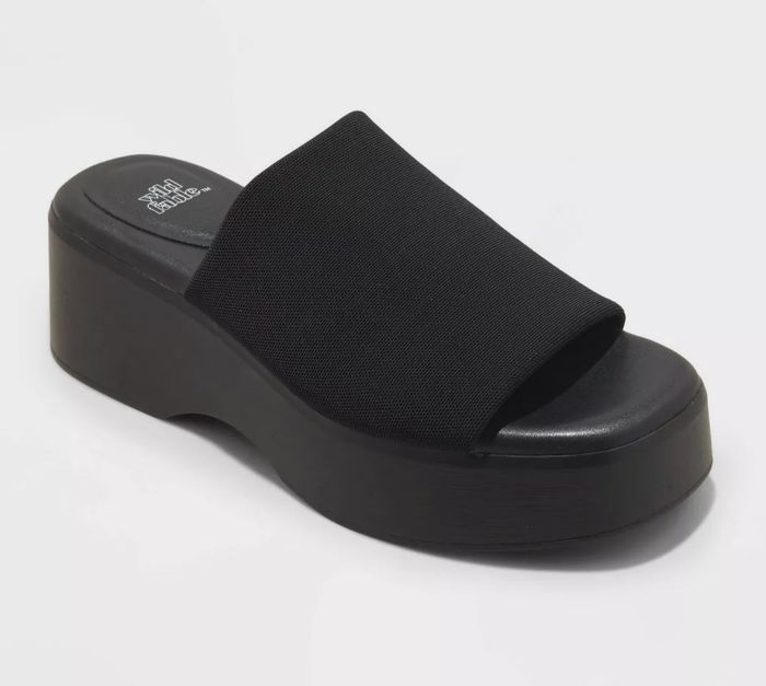 A black platform slide sandal featuring a wide fabric strap and a thick sole