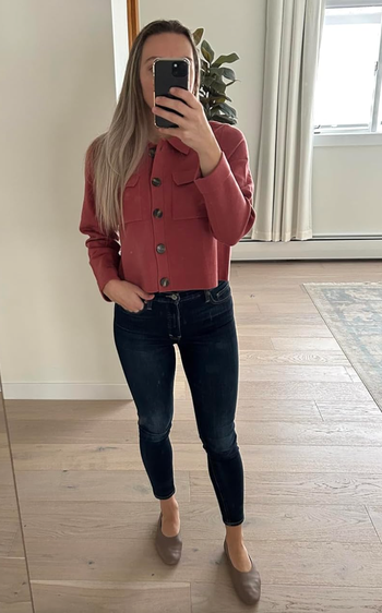 A person taking a mirror selfie in a button-up red jacket.