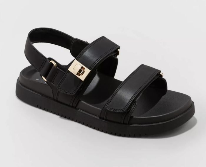 Black strappy sandal with a buckle detail against a soft background