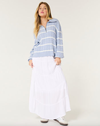 A model wearing a striped sweater paired with a long skirt and sneakers.