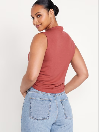 A model styled in a sleeveless salmon top and jeans.