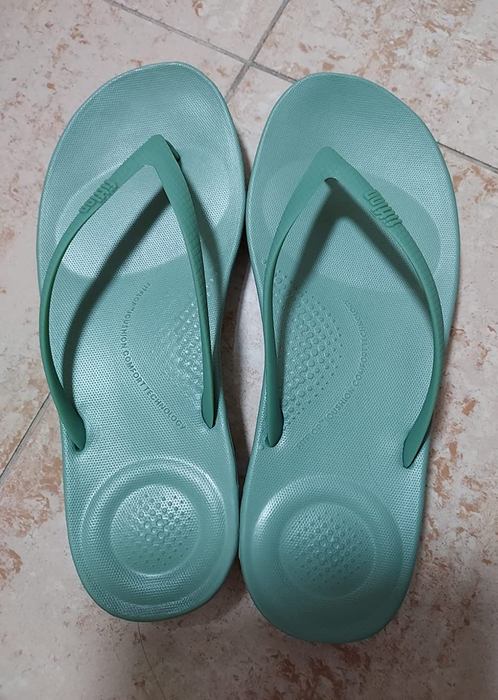 Reviewer photo showing teal flip-flops with cushioned soles.