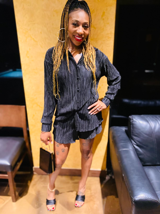another reviewer posing indoors in a black textured blouse and matching shorts set