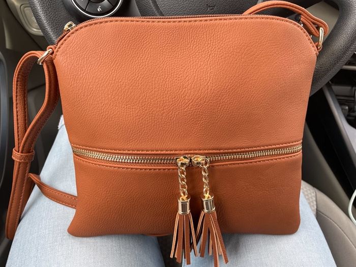 Reviewer holding a Deluxity crossbody bag in the 