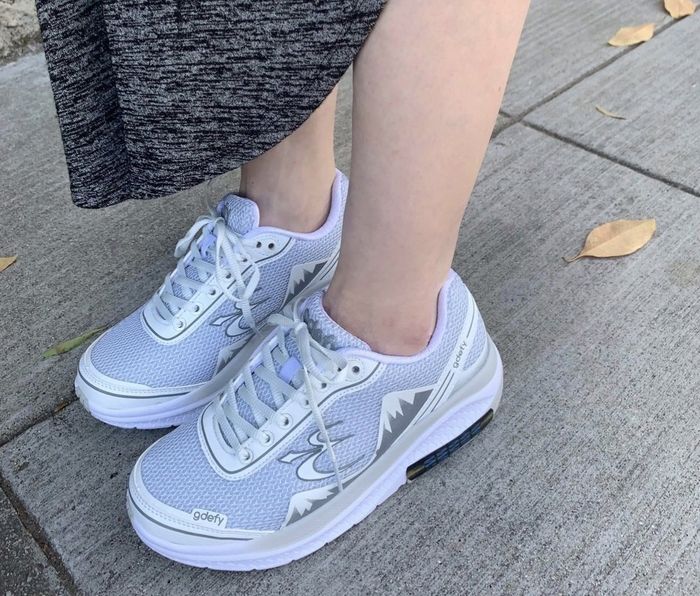 A reviewer modeling grey sneakers