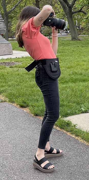 A photographer is wearing black Crocs sandals.