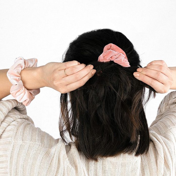 A model wearing one of the scrunchies in a pretty pink shade