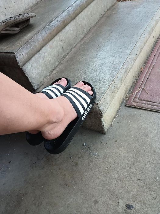 A foot wearing Adidas slide sandals on concrete steps, featured in an article about casual footwear shopping