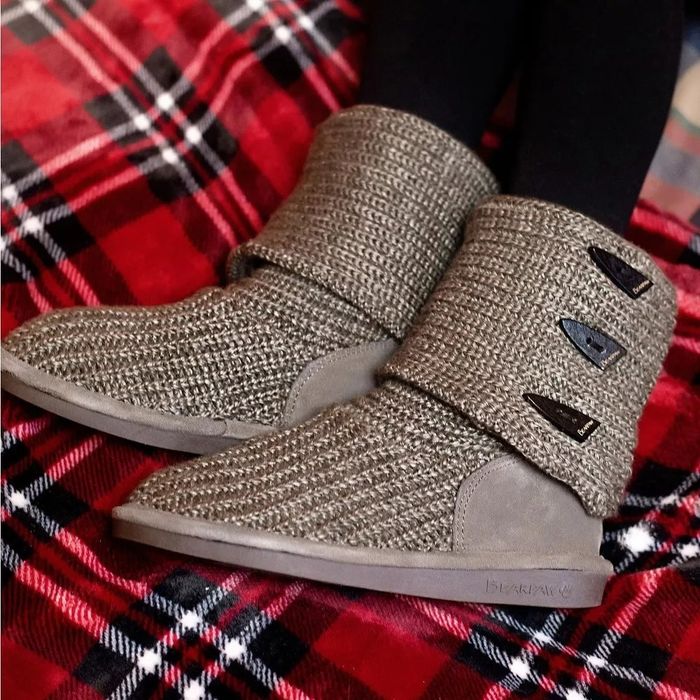 A model showcasing tan textured knit ankle boots against a plaid backdrop