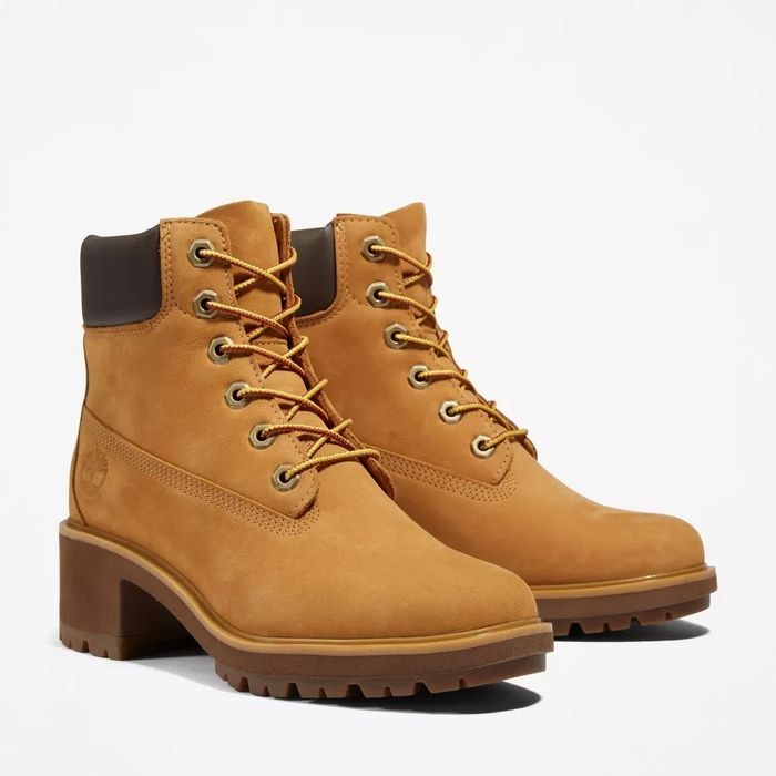 A pair of mustard-colored lace-up boots with the Timberland logo on the side