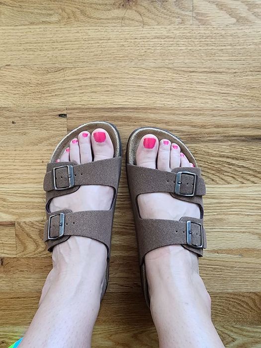A reviewer wearing the sandals in brown vegan suede