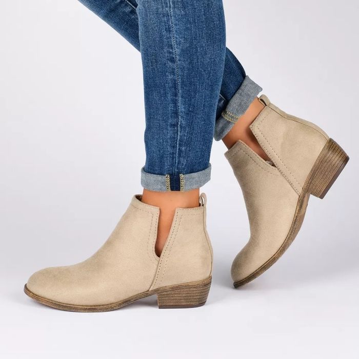 A person in jeans sporting beige ankle boots with low heels