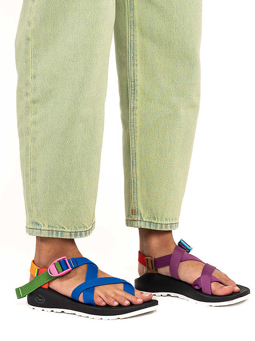 A person in green pants showcasing multicolored strappy sandals