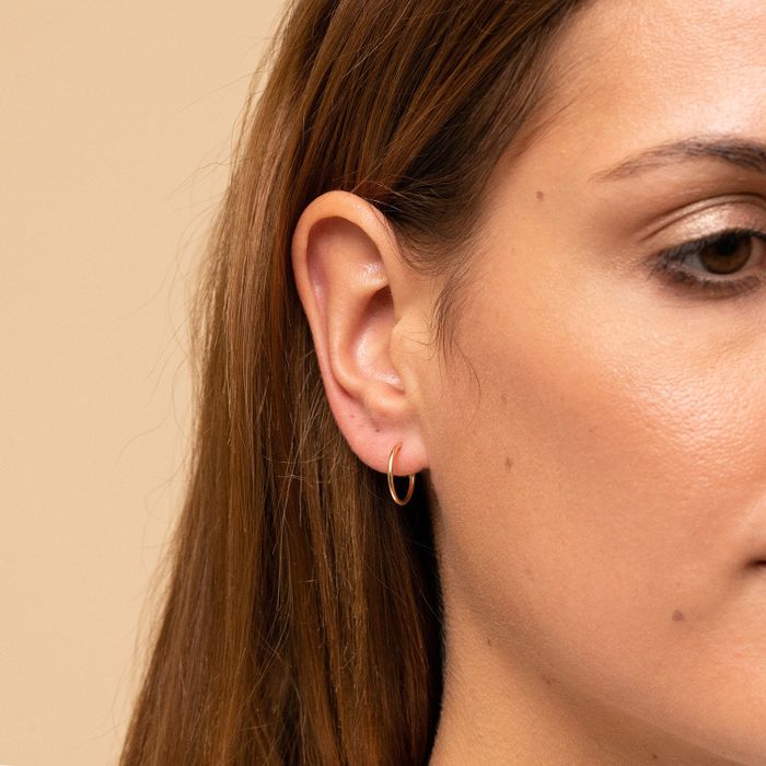 Model wearing a small gold hoop earring