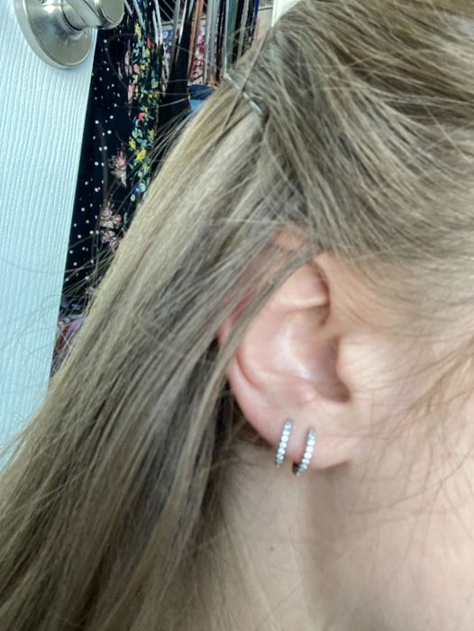 Two huggie hoop earrings worn on the reviewer's ear