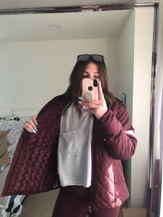 A reviewer showcasing a red coat paired with a grey top and red bottoms