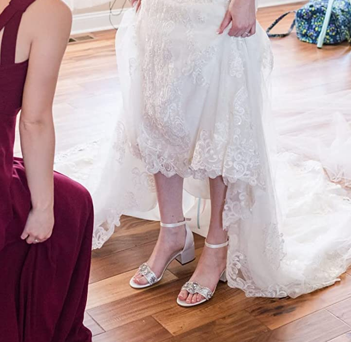 A reviewer wearing the sandals with a wedding dress