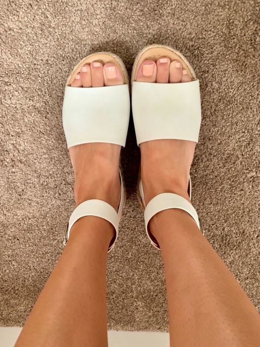 A reviewer wearing the white sandals