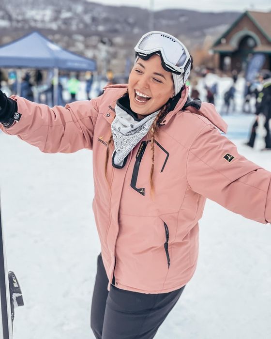 A reviewer showcasing a pink coat styled with grey pants