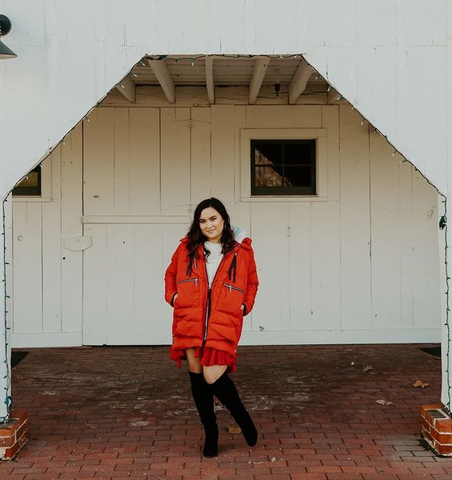 A reviewer sporting a red coat paired with black boots and a white top