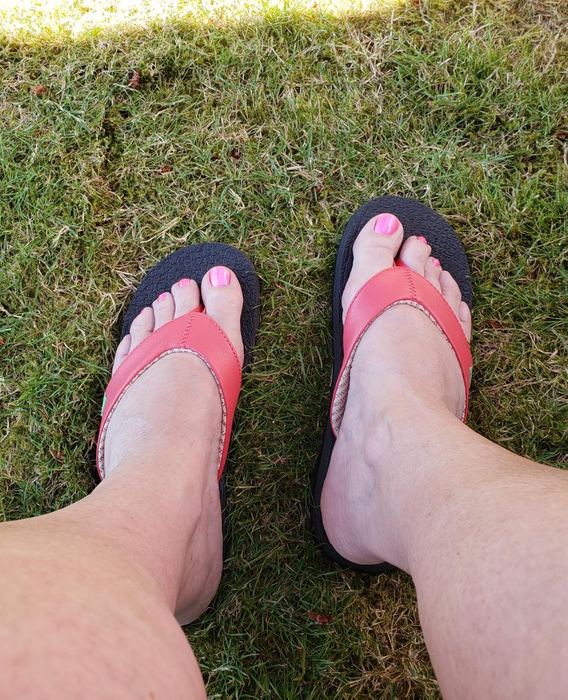 A reviewer showcases the flip-flops, wearing them in vibrant orange.