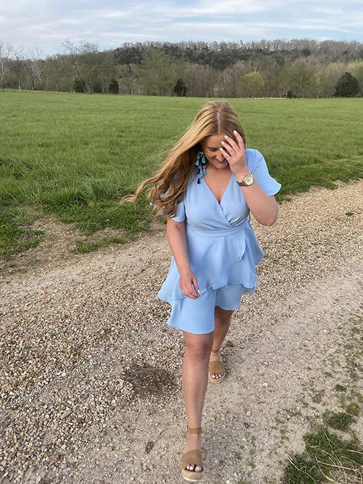 A reviewer photo of them wearing the blue mini wrap dress with short sleeves