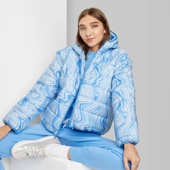 Model wearing the hooded puffer jacket in light blue with a swirly pattern
