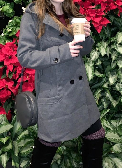 A reviewer wearing a grey coat styled with a black outfit
